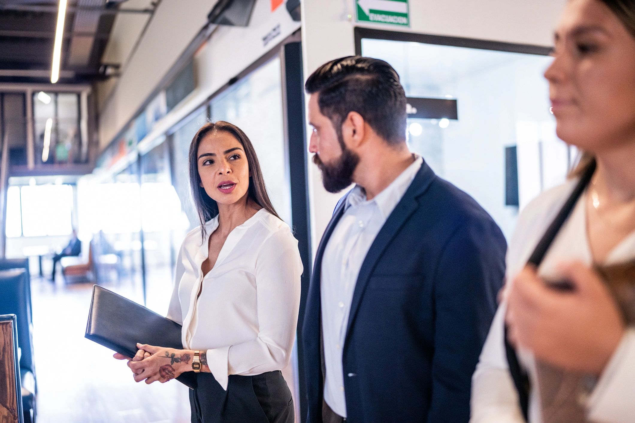 Profesionales mexicanas y mexicanos caminando y conversando en una oficina moderna